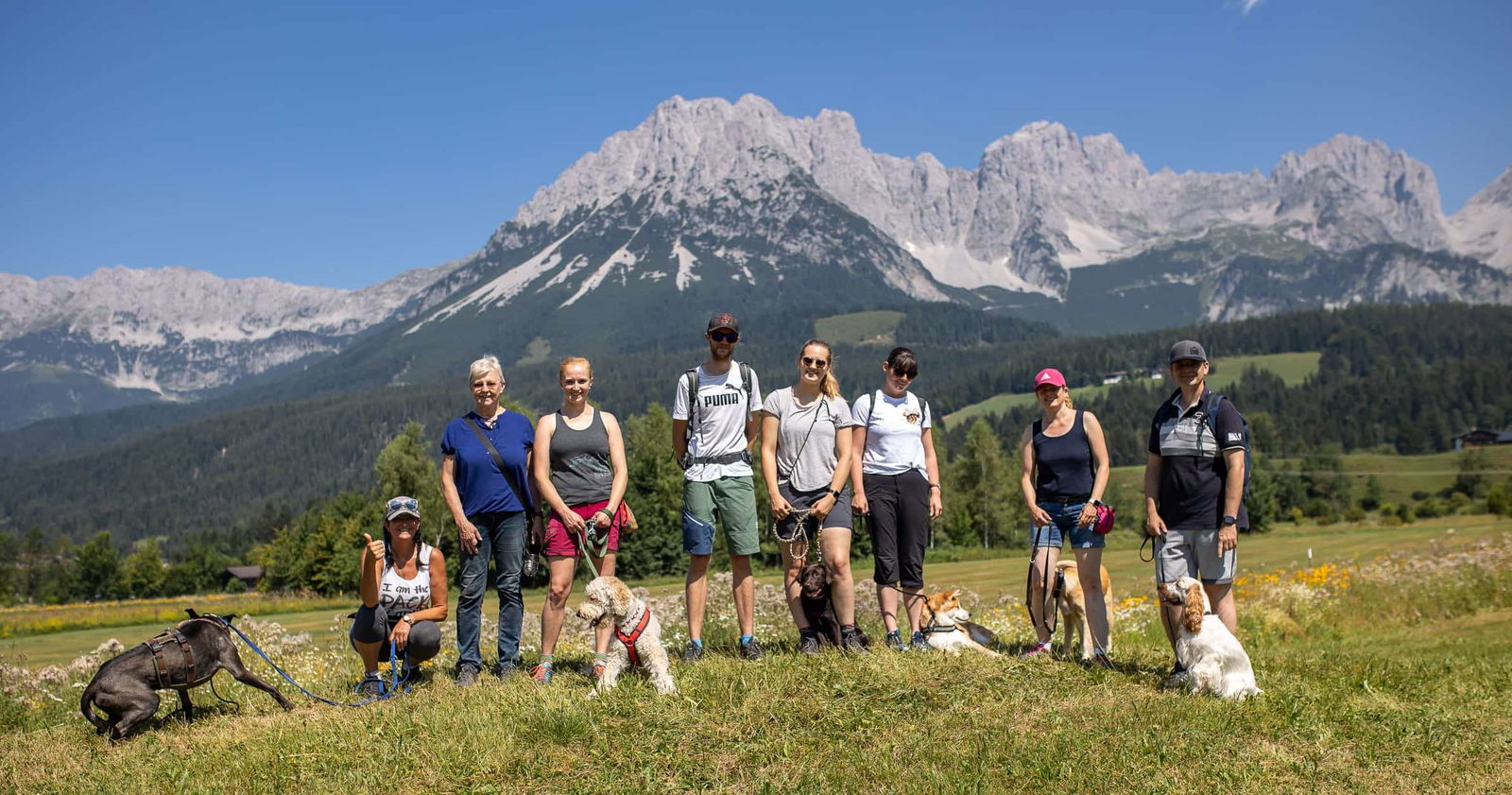 Gruppenfoto des Hunde-Pack Walks in Ellmau mit Coachin Hedwig vor dem Wilden Kaiser.